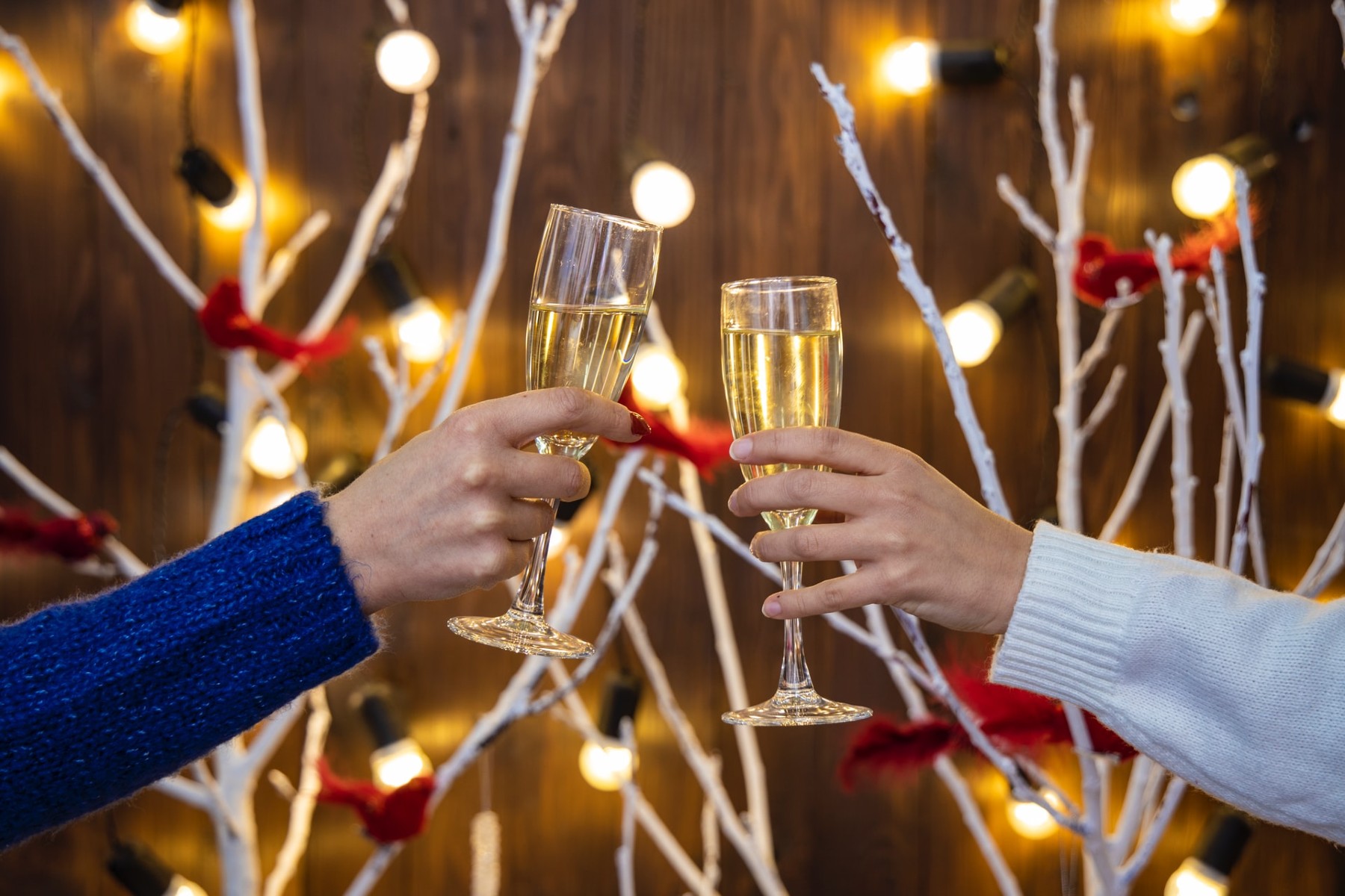 two glasses of champagne are held up in front of a backdrop of festive lights