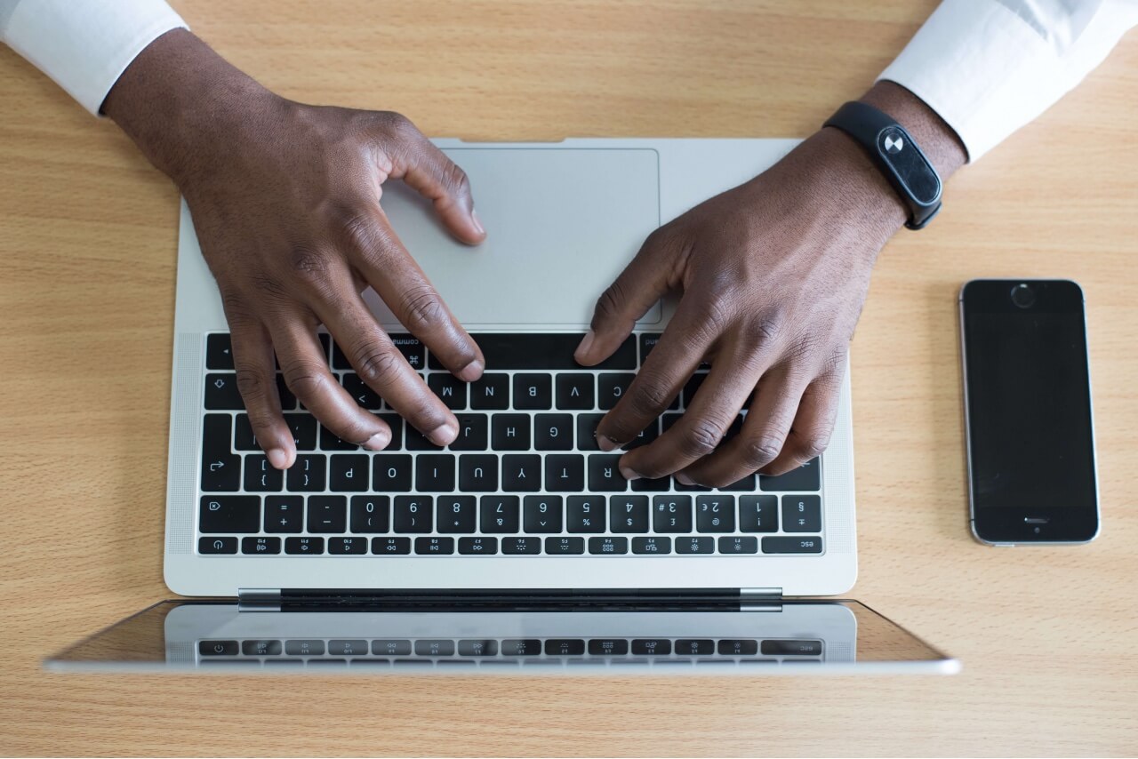 person working on laptop with phone beside them