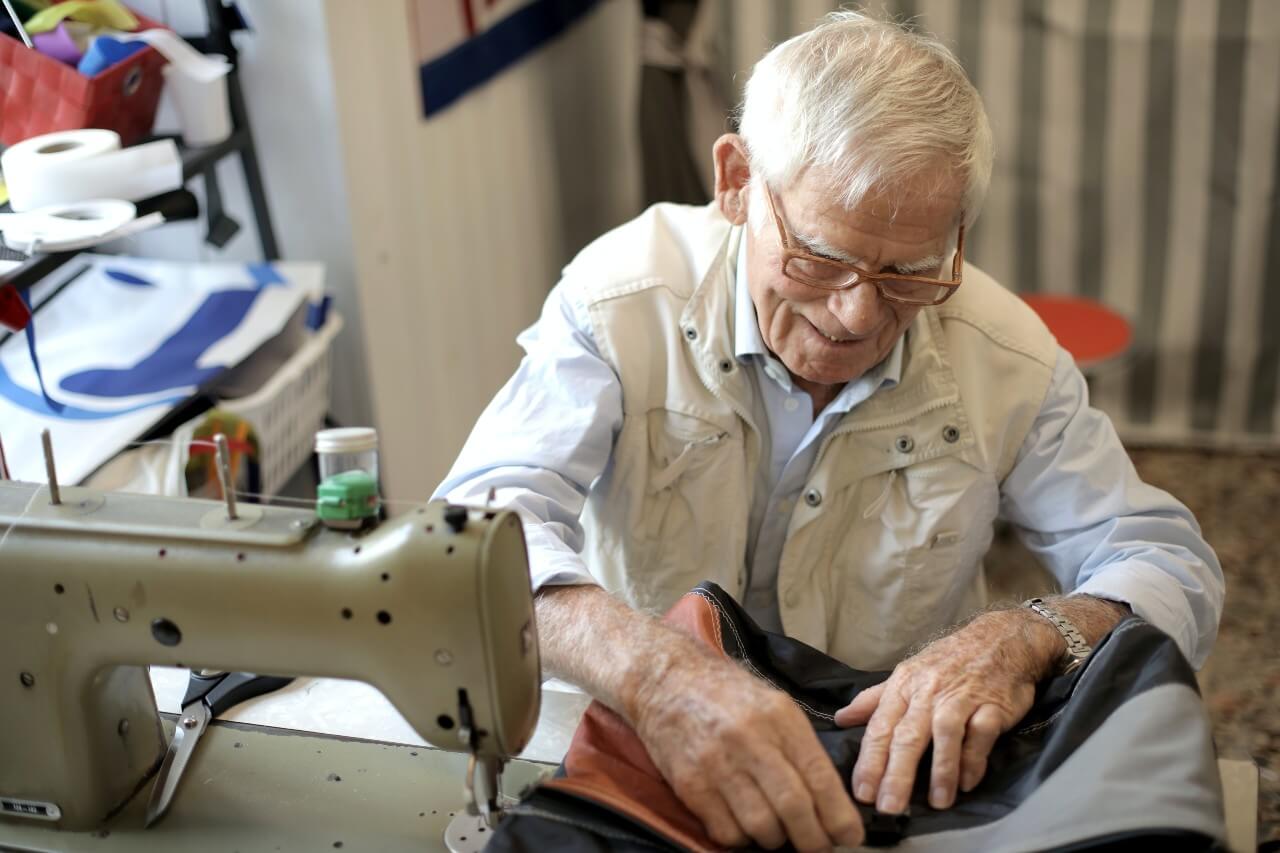 An elderly gentleman uses a sewing machine