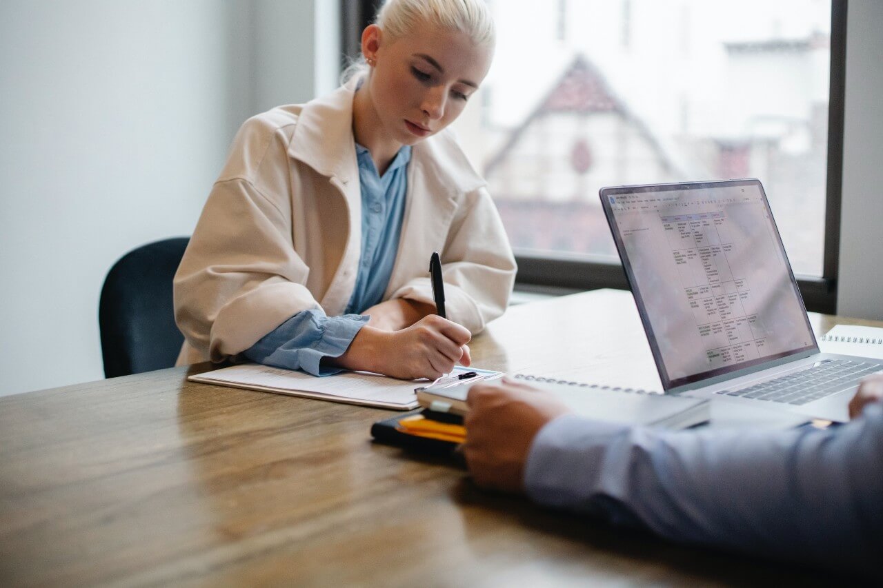 Woman with blonde hair makes notes during a meeting