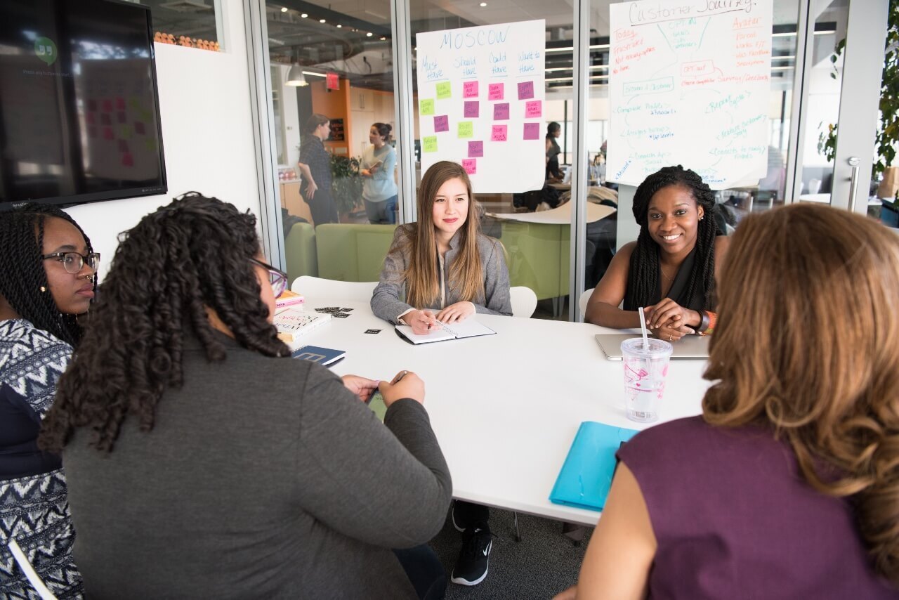 A group of female colleagues sit around a table