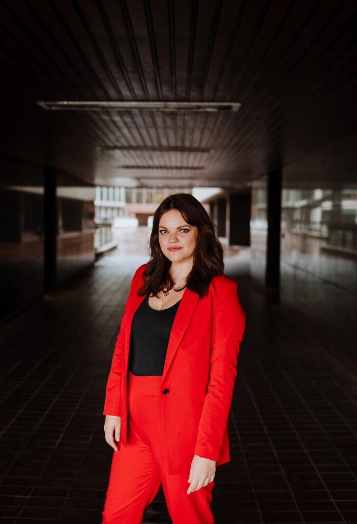 Kirsty Hulse is posing for a photo, and wearing a powerful red suit