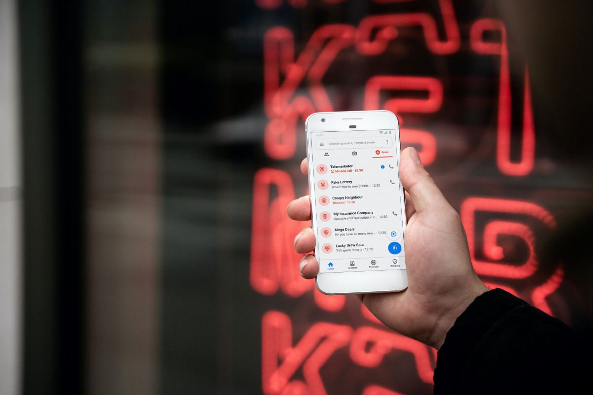 person holding a phone, displaying a call log of scams