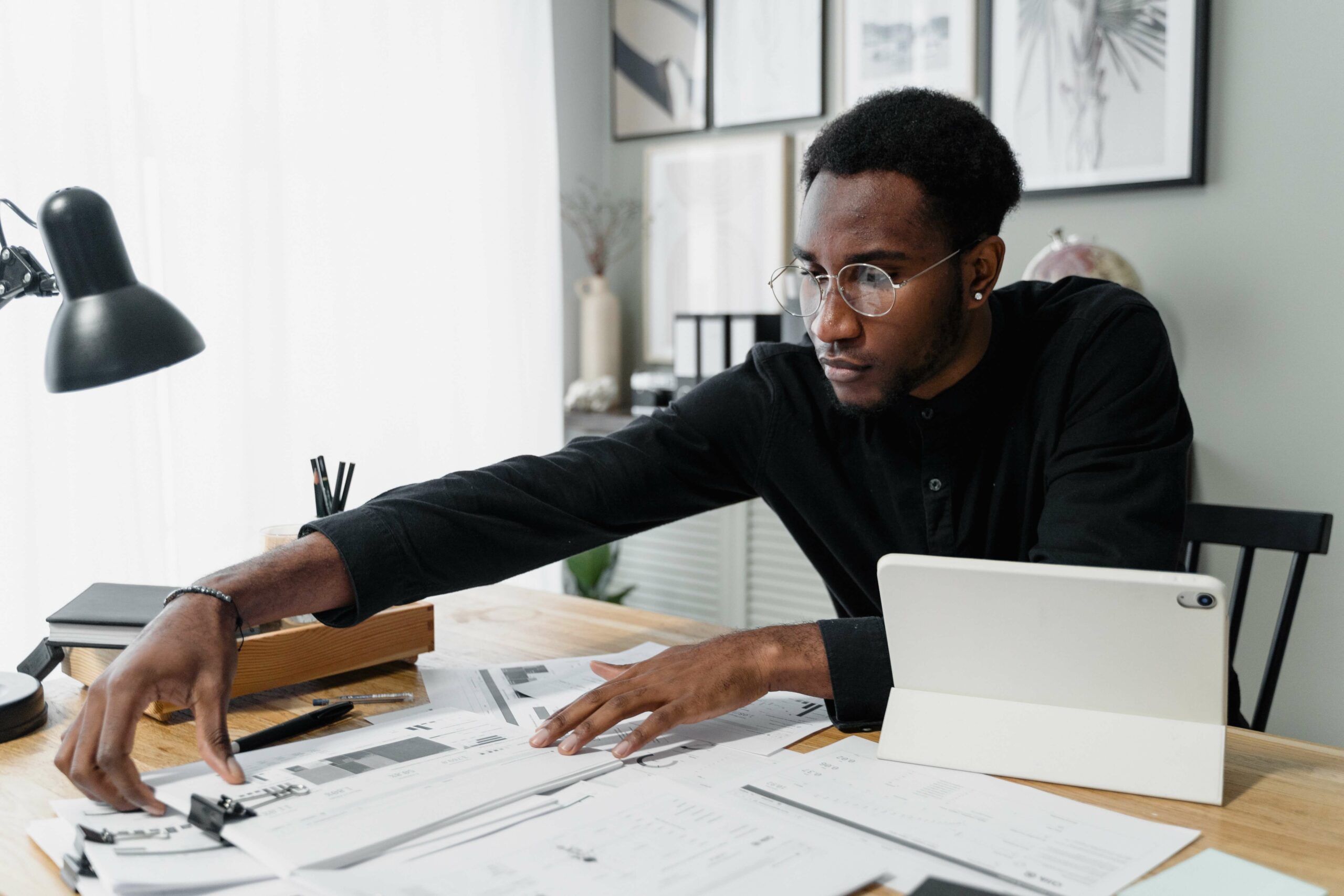 A man in a black jumper works through timesheets at a desk