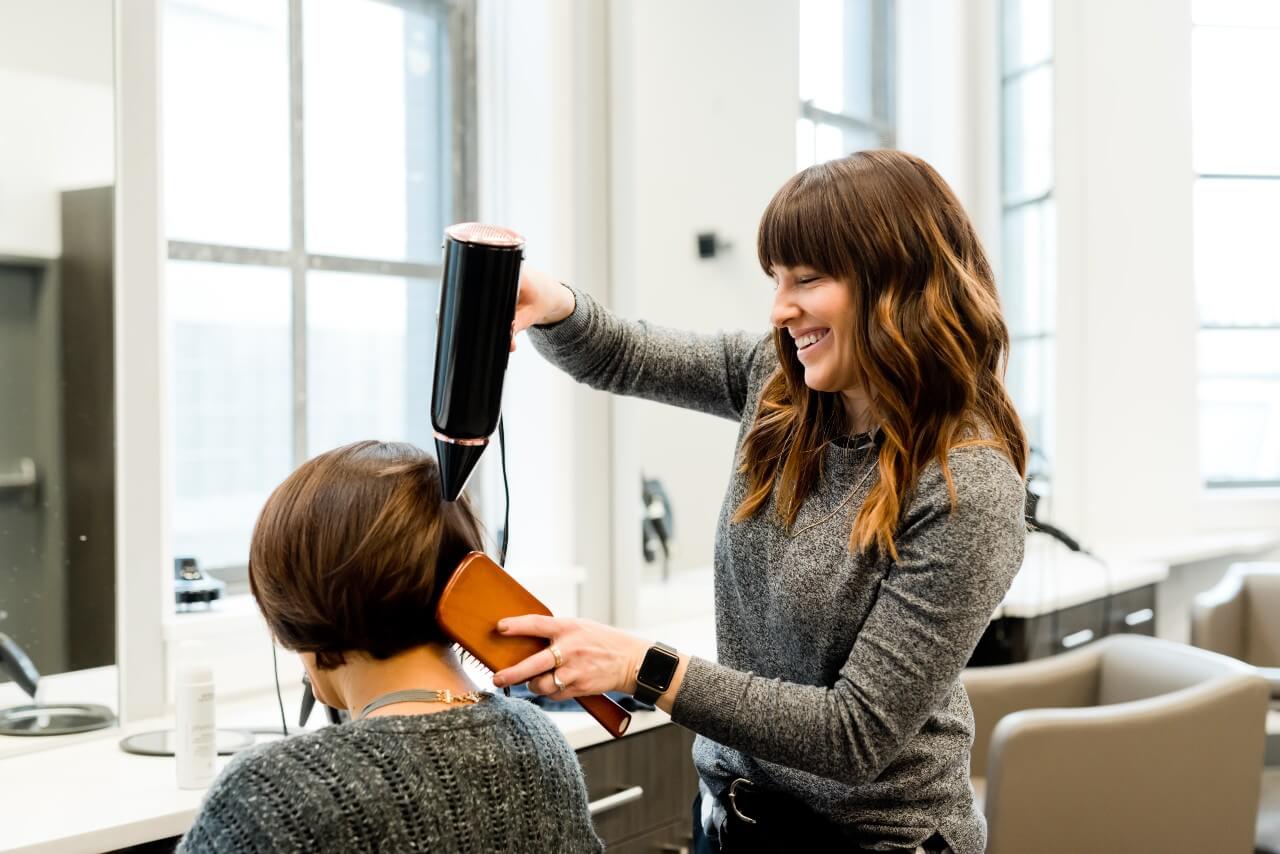 A hairdresser blowdries her client's hair