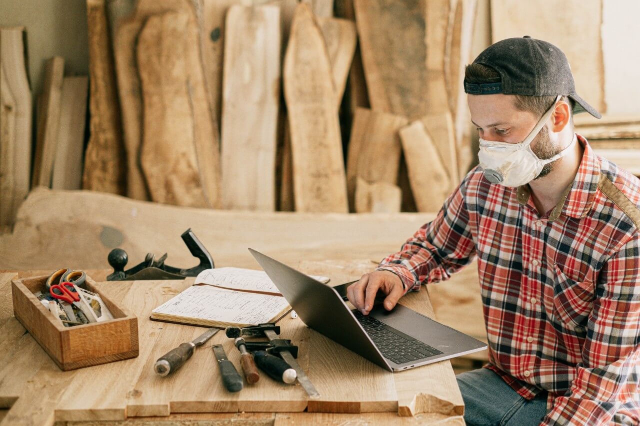 Man using a laptop in a woodworking workshop