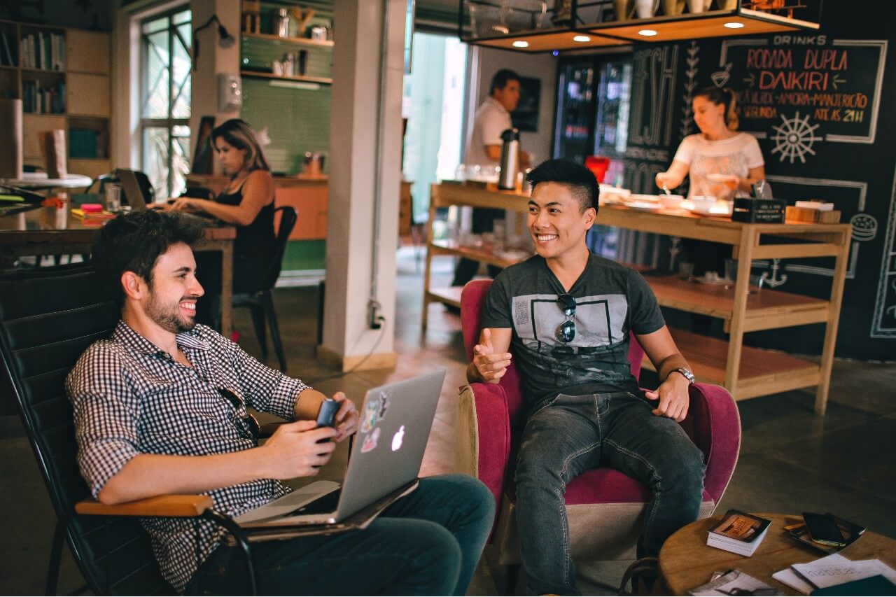 Two male colleagues laugh together in the workplace